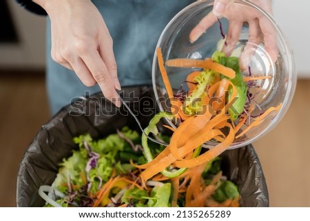 Compost the kitchen waste, recycling, organic meal asian young household woman scraping, throwing food leftovers into the garbage, trash bin from vegetable. Environmentally responsible, ecology. Royalty-Free Stock Photo #2135265289
