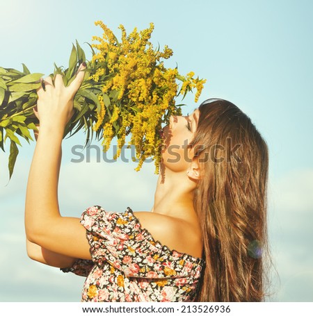 Summer portrait of beautiful dark-haired girl with a bouquet in hand enjoying the sunshine.side view.Photo tinted light yellow to transfer summer atmosphere  