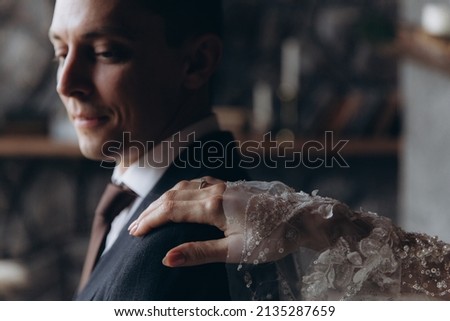 The first meeting of the groom in a black suit and the bride in a white wedding dress with a bouquet in the interior of a photo studio, hotel, on black background	
