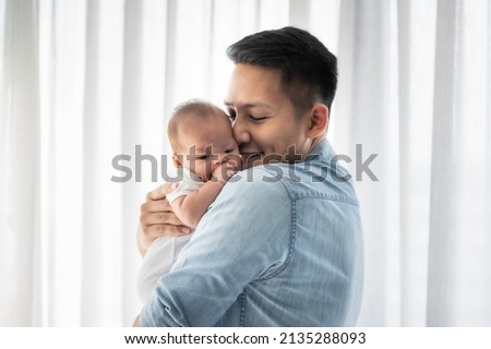 Asian father holding baby daughter and kissing with love at home  Royalty-Free Stock Photo #2135288093