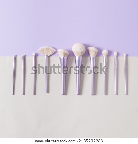 Different makeup brushes on a pastel violet background. Magazine, social media. Beauty and Fashion. Visagist tools. Top view, close up. Creative flat lay. Cosmetics products