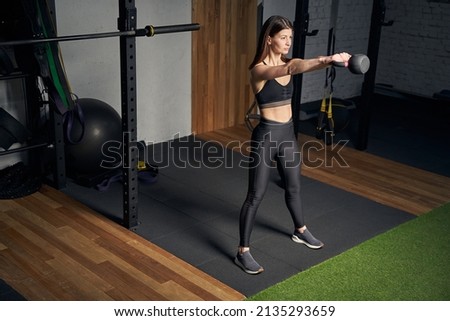 Sporty woman doing exercise with kettlebell in gym