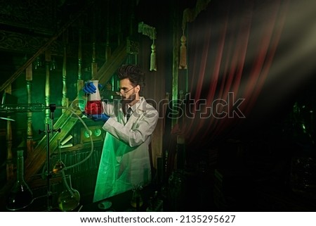 A possessed scientist makes experiments in his dark, mysterious laboratory to invent a magical elixir.  Royalty-Free Stock Photo #2135295627
