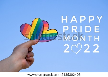 Human hands holding rainbow hearts with texts 'Happy Pride Month 2022', concept for lgbt celebrations in pride month, June, every year, everywhere around the world.