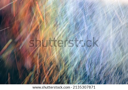 Abstract raindrops nature background. Rain on long exposure. Rain drops motion. Trails of falling raindrops and rainbow colors