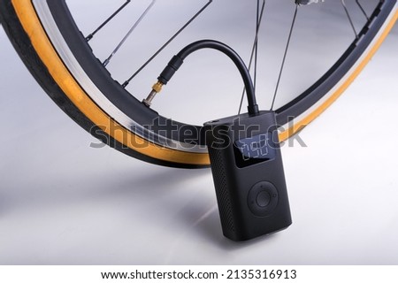Portable cordless tire inflator. Portable air pump inflate a bike tire Royalty-Free Stock Photo #2135316913