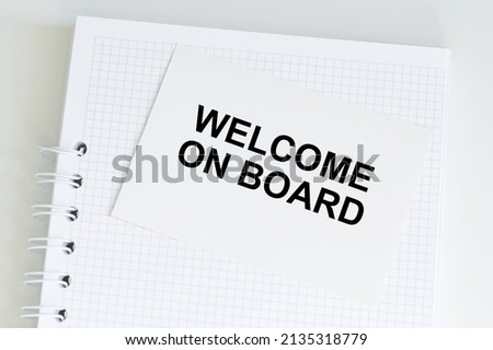 welcome on board text on a white card on a table with notepad in isolation