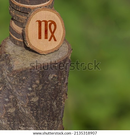 Close-up shot of a piece of wood with a zodiac sign engraved on it, especially the virgo sign