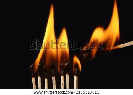 Lighted match next to row of burning matches on black background. Inspiration concept Royalty-Free Stock Photo #2135319611