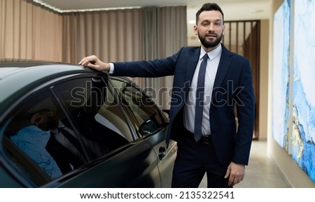 respectable businessman in a garage next to a prestigious premium car. the concept of success and stability in business Royalty-Free Stock Photo #2135322541