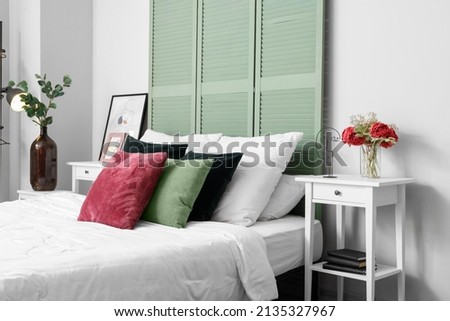 Interior of light bedroom with green folding screen and tables