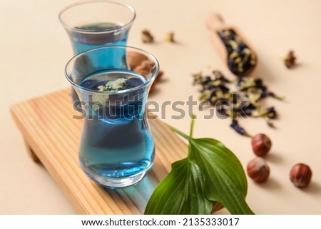 Cups of blue tea on color background, closeup