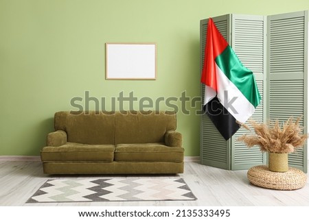 Interior of stylish living room with sofa, folding screen and UAE flag