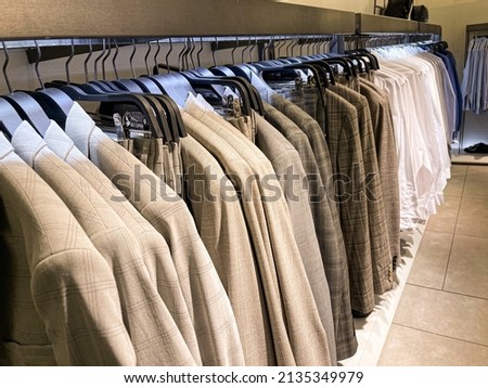 Mens fashion suits ,shirt, pants 
on hanger in a retail clothes store
