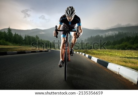 A young man trains on a road bike, in the mountains. Royalty-Free Stock Photo #2135356659