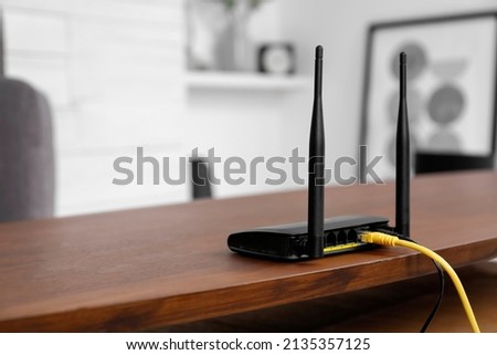 Modern Wi-Fi router on wooden table indoors. Space for text