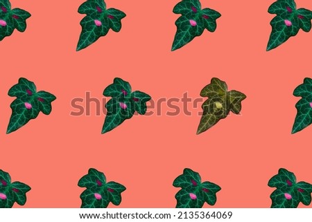green futuristic leaves and one yellow on pastel orange background, break the pattern, creative futuristic natural background with leaves that have facial expression