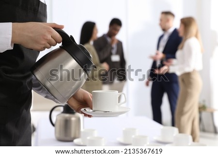 Waitress pouring hot drink during coffee break, closeup Royalty-Free Stock Photo #2135367619