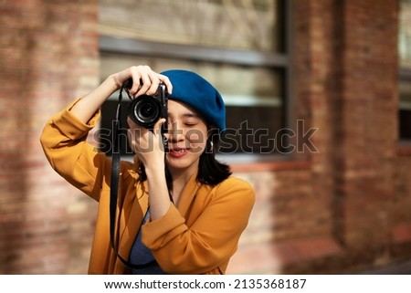 Beautiful Chinese woman with camera. Happy smiling woman taking photos of beautiful location	