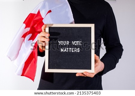 man with Canada flag holding letter board with text Your Vote Matters on white background