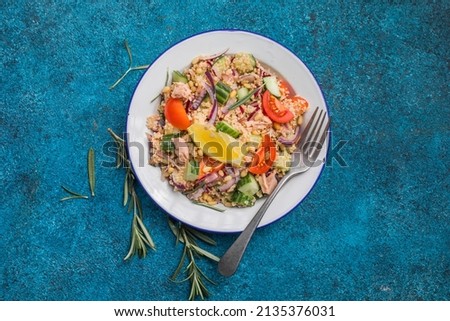 Food dieting concept, tuna salad. Couscous salad with conserved tuna, tomatoes, cucumbers and purple onions on table. Copy space. Royalty-Free Stock Photo #2135376031