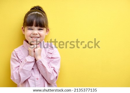 Little girl laughing. Caucasian Girl screw up eyes with laughter, cute caucasian kid in blouse isolated over yellow background