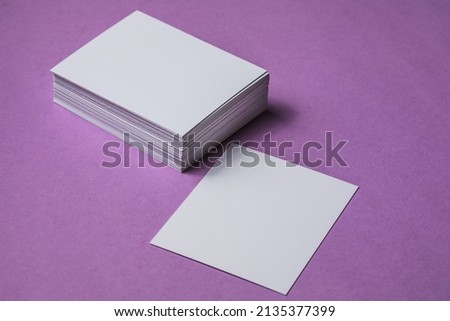 White sheet mockup. Stack of blank name cards. Blank white business card on purple paper background. 