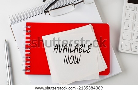 AVAILABLE NOW word on sticker on notepad with pen and calculator