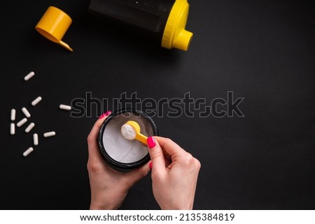 Creatine. A woman's hand holds a portion of sports nutrition on a black background close-up. Royalty-Free Stock Photo #2135384819