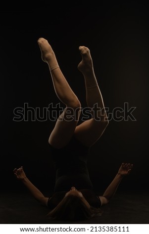 Beautiful female silhouette  of ballerina laying with her legs up