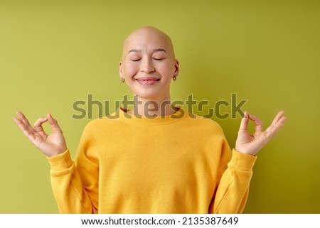 Keep calm, yoga. Portrait of young caucasian bald woman isolated on green studio background. Good-looking female model with eyes closed. Human emotions, facial expression, sales, ad concept. Youth