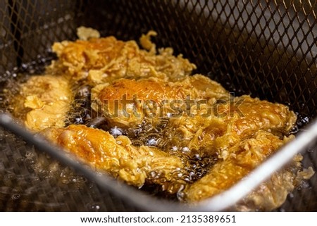 Crispy chicken Nuggets in boiling hot oil. Making crispy in the fryer hot oil. Fast food concept. Royalty-Free Stock Photo #2135389651