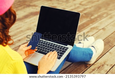 Close up woman working with laptop and smartphone on wooden table or floor background, black screen, top view
