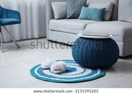 Stylish living room interior with comfortable sofa, knitted pouf and modern laptop. Space for text Royalty-Free Stock Photo #2135395205