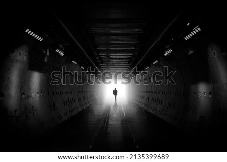 Dreaming, man in dark tunnel. Freedom light in tunnel. Silhouetted desaturated. Silhouette of a woman walking into the light. Light at the end of the tunnel. business man in silhouette walking Royalty-Free Stock Photo #2135399689
