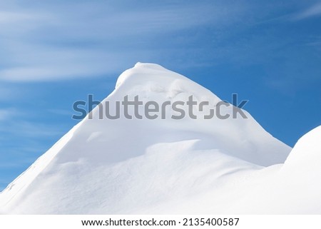 A large pile of snow after a blizzard and snowfall looks like mountain peaks. Royalty-Free Stock Photo #2135400587
