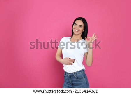 Happy woman touching her belly and showing okay gesture on pink background, space for text. Concept of healthy stomach Royalty-Free Stock Photo #2135414361