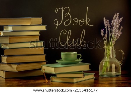 Book Club, toned image. Stacks of books and a cup of coffee with chalk lettering on a blackboard and lavender flowers