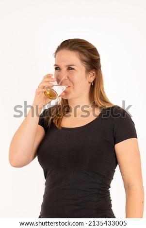 A young woman drinks a glass of water. Isolated with white background.