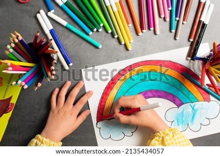 POV child painting a picture with school supplies, preschool child painting, child drawing a rainbow, child doing homework. Royalty-Free Stock Photo #2135434057