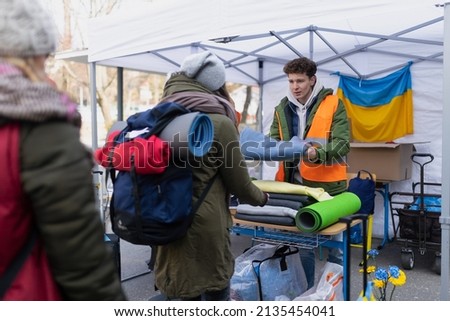 Volunteers distributing blankets and other donations to refugees on the Ukrainian border. Royalty-Free Stock Photo #2135454041