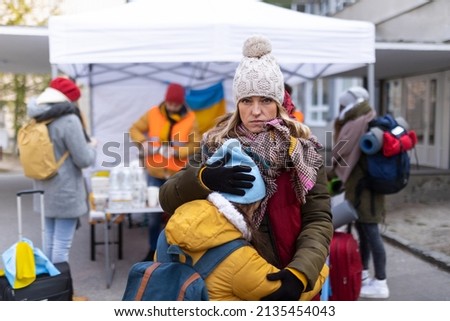 Ukrainian refugee mother with child crossing border and looking at camera. Royalty-Free Stock Photo #2135454043