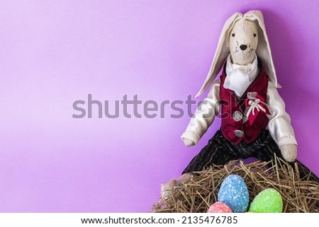 Easter greeting card with decorative eggs, rabbit and text space on a purple background. minimalism