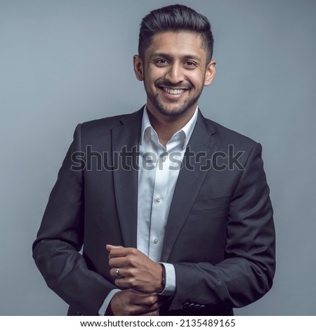 Young indian asian man wearing black suit and white shirt over isolated grey or white background happy face smiling with crossed arms looking at the camera. Positive person.