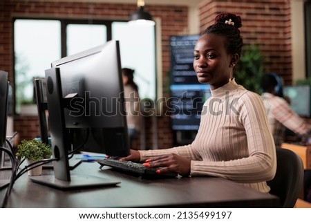 Tech engineer creating machine learning software to be used as an autonomous virtual entity. Confident african american network developer engineering application for company database. Royalty-Free Stock Photo #2135499197