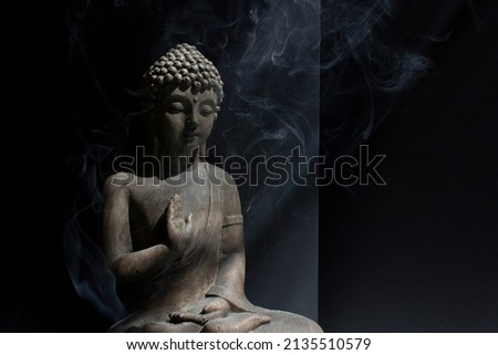Stone Buddha statue into sun light on dark background