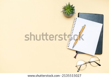Black blank notebook, pen, glasses, goggles top view on beige background. Top view desk arrangement. Time management, planning concept. Minimal style, mock up with copy space, template logo design.