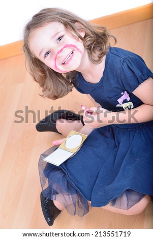 Little cute girl using make-up to turn herself into clown