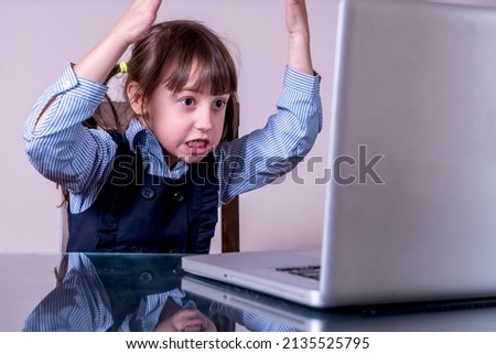 Very angry young girl sitting in front of laptop screen 
