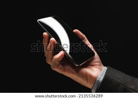 Smartphone device in hand of elegant businessman, low key image with selective focus
